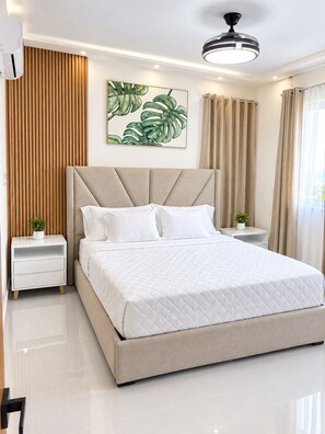 Ein modernes Schlafzimmer mit einem großen Bett, einem Nachttisch, einer Wandleuchte und einem an der Wand hängenden Kunstwerk.