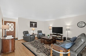 Una sala de estar moderna con un sofá, dos sillones, una mesa de centro, un televisor y un cráneo de toro decorativo en la pared.