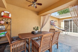 A covered patio with a wooden table and chairs, a ceiling fan, a hammock, and a pool table. - Spacious 4BR/2BA Roseville Oasis w/ Pool & Lounge (Roseville)