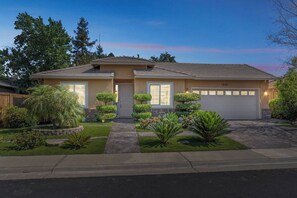 A two-story house with a front garage, a well-maintained lawn, and a variety of shrubs and plants. - Spacious 4BR/2BA Roseville Oasis w/ Pool & Lounge (Roseville)