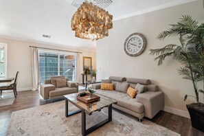 A living room with a sofa, coffee table, and a large wall clock. - Spacious 4BR/2BA Roseville Oasis w/ Pool & Lounge (Roseville)