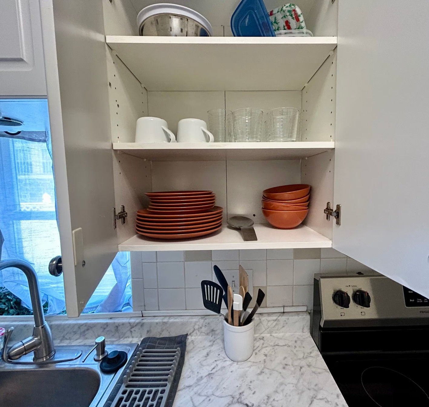 A kitchen with white cabinets, a sink, and a stove.