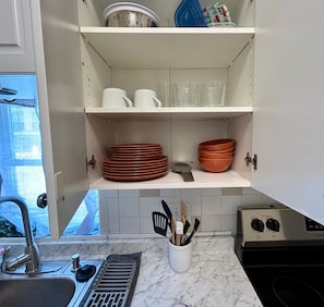 A kitchen with white cabinets, a sink, and a stove.