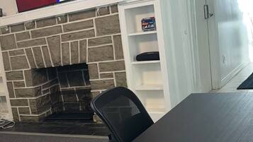 A conference room with a stone fireplace, a flat-screen TV mounted above it, and a table with office chairs.