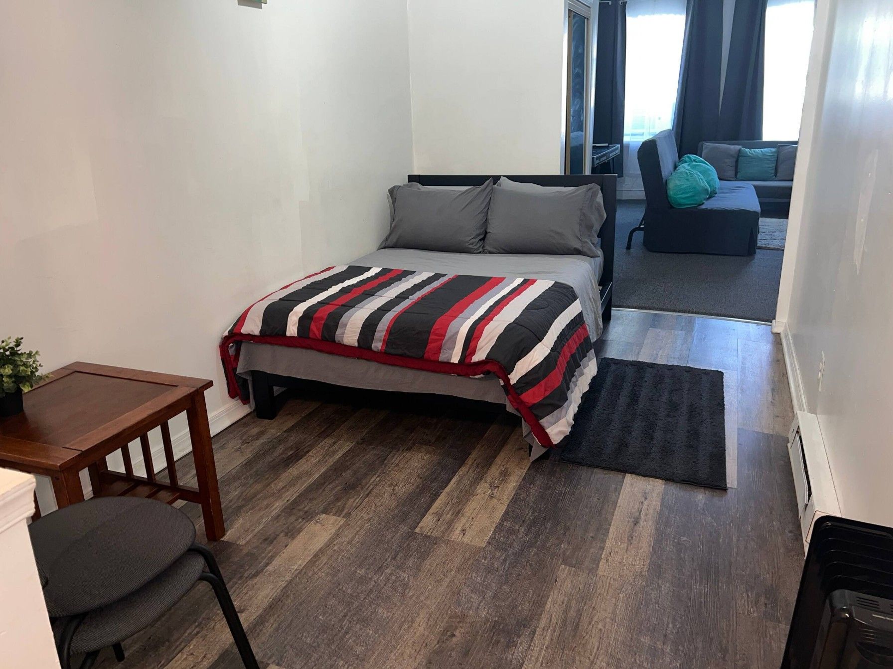 A bedroom with a bed, a desk, a chair, and a sofa.