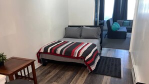 Ein Schlafzimmer mit einem Bett, einem Schreibtisch, einem Stuhl und einem Sofa.