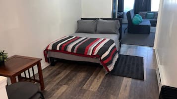 A bedroom with a bed, a desk, a chair, and a sofa.