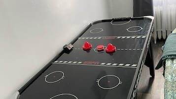 Un biliardo con una biglia rossa e due bersagli rossi, una finestra con tende e un quadro floreale al muro.