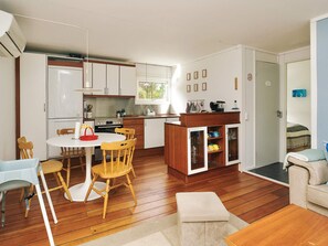 A compact kitchen with a dining area, wooden flooring, and a small seating space. - 4 Person Holiday Home in Hojby (Hojby)
