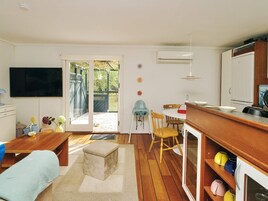 Un espacio habitable compacto con kitchenette, comedor y puerta corrediza de vidrio que da a un área exterior.