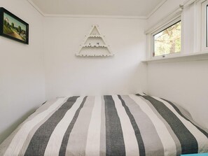 A bedroom with a bed, a window, and a wall-mounted shelf. - 4 Person Holiday Home in Hojby (Hojby)