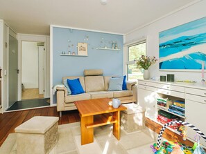 A living room with a sofa, a coffee table, a bookshelf, and a painting on the wall. - 4 Person Holiday Home in Hojby (Hojby)