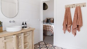 Un bagno con un lavandino bianco, mobiletti in legno, uno specchio e un portascope con asciugamani.
