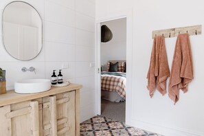 A bathroom with a white sink, wooden cabinets, a mirror, and a towel rack with towels. - Luxury and comfort in the heart of Dunkeld, with the Grampians at your doorstep! (Dunkeld)