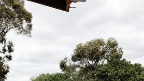 Zona esterna con tavoli e sedie, circondata da un recinto e alberi.