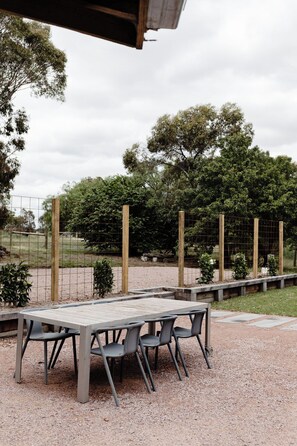 An outdoor seating area with a table and chairs, surrounded by a fence and trees. - Luxury and comfort in the heart of Dunkeld, with the Grampians at your doorstep! (Dunkeld)