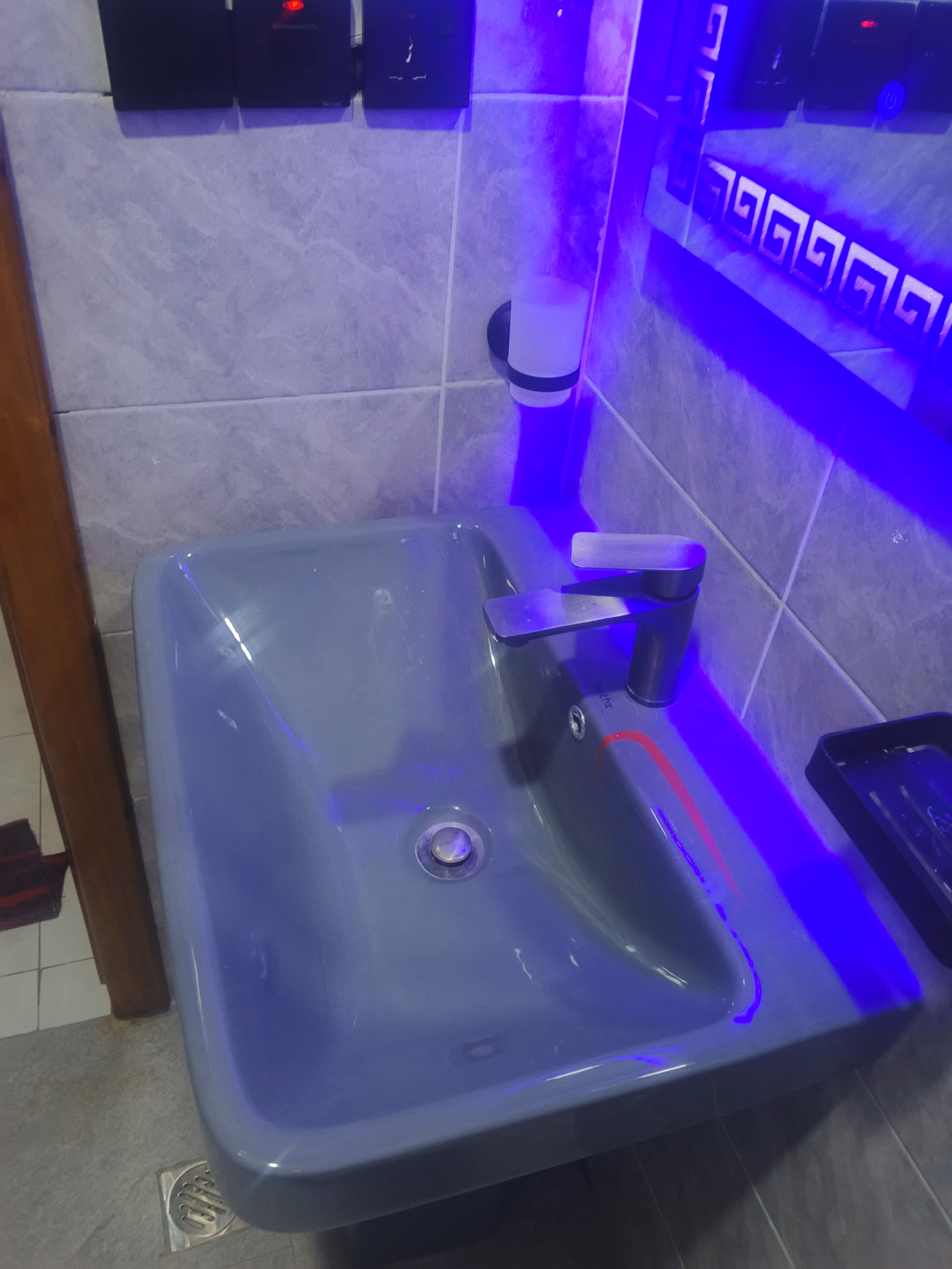 Ein Badezimmer mit blauem Waschbecken, einem Spiegel und einer Seifenspender an der Wand.