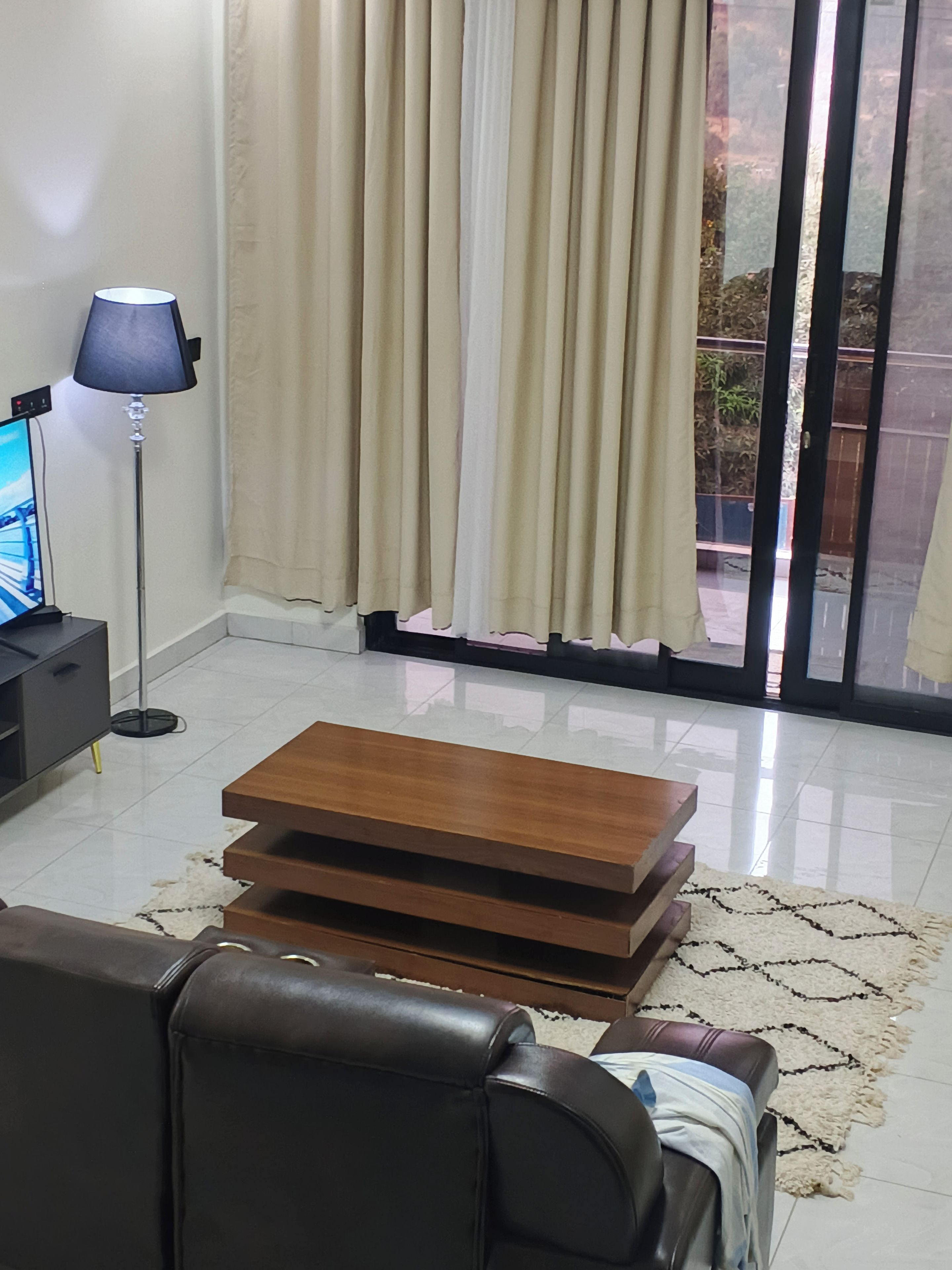 A living room with a sofa, a coffee table, a lamp, and a TV on a stand.
