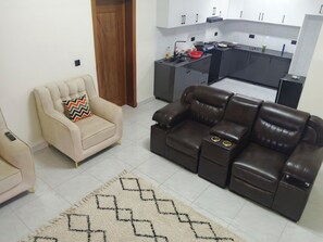 Un salon avec un canapé beige, un canapé en cuir marron et un tapis à motifs.