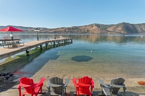 A lakeside view with clear water, a dock, and chairs for seating. - The Red Lake House | Beach & Dock Access (Chelan)