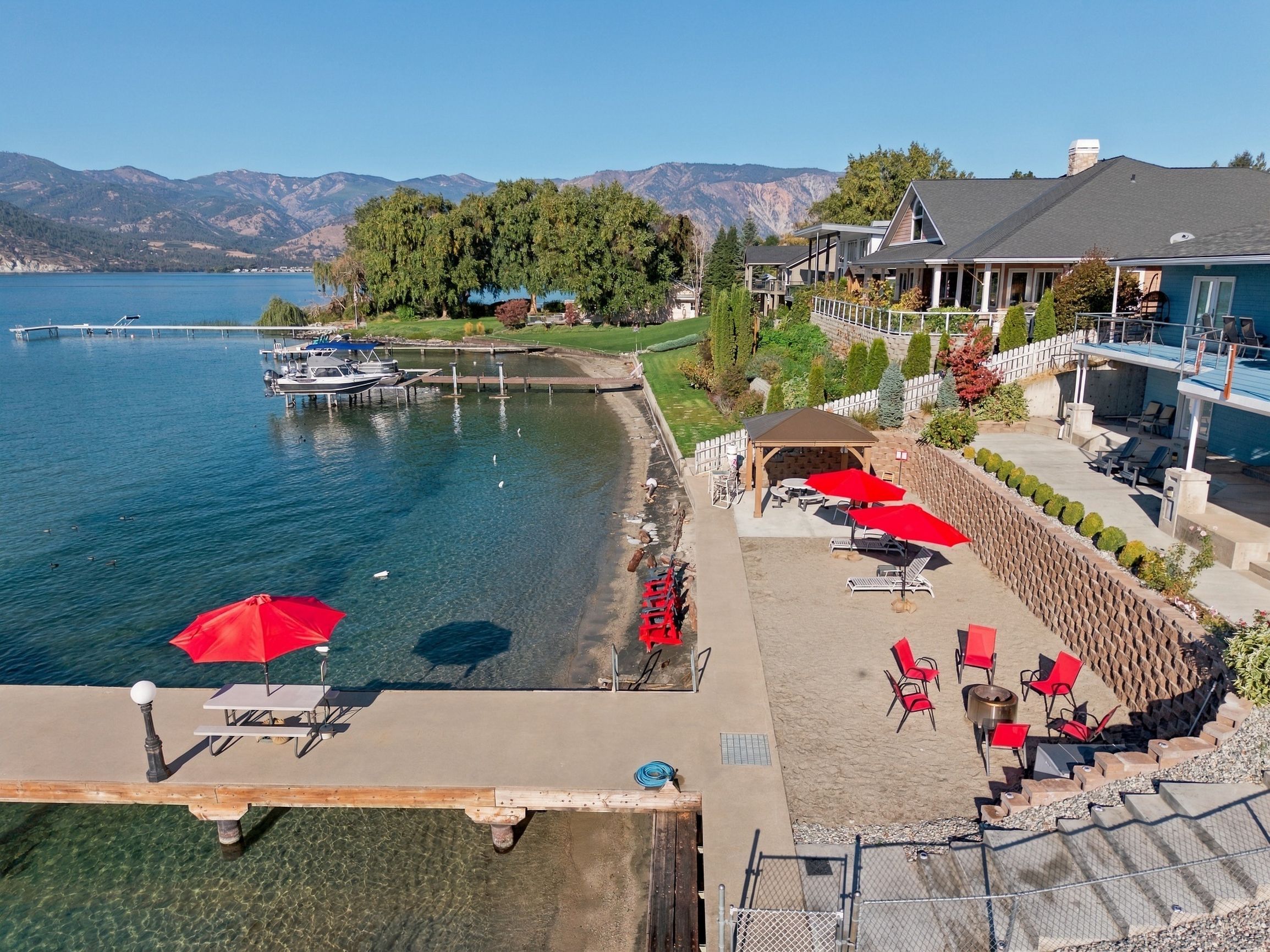 A lakeside property with a dock, outdoor seating, and a view of mountains.
