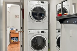 A stacked white washer and dryer positioned in a dedicated alcove. - The Red Lake House | Beach & Dock Access (Chelan)