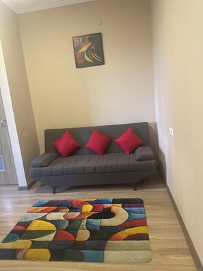 A living room with a grey sofa, three red cushions, and a colorful abstract rug. - Perfect 1-bedroom apartment with AC in amazing Yerevan (Yerevan)