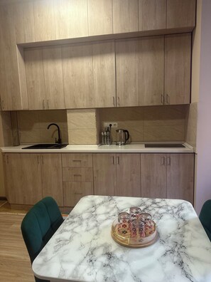 A kitchen with wooden cabinets, a marble countertop, and a dining table with chairs. - Perfect 1-bedroom apartment with AC in amazing Yerevan (Yerevan)