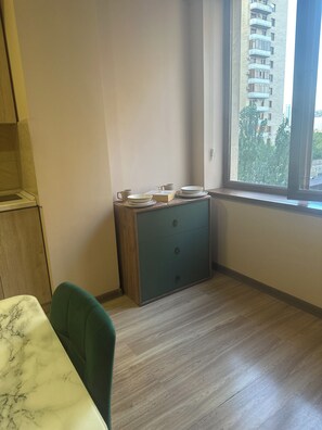 A corner of a room with a wooden cabinet, a green chair, and a window with a view of a building. - Perfect 1-bedroom apartment with AC in amazing Yerevan (Yerevan)