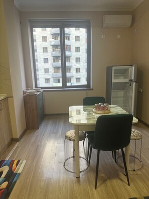 A dining area with a table, chairs, a window with a view of buildings, and an air conditioning unit. - Perfect 1-bedroom apartment with AC in amazing Yerevan (Yerevan)