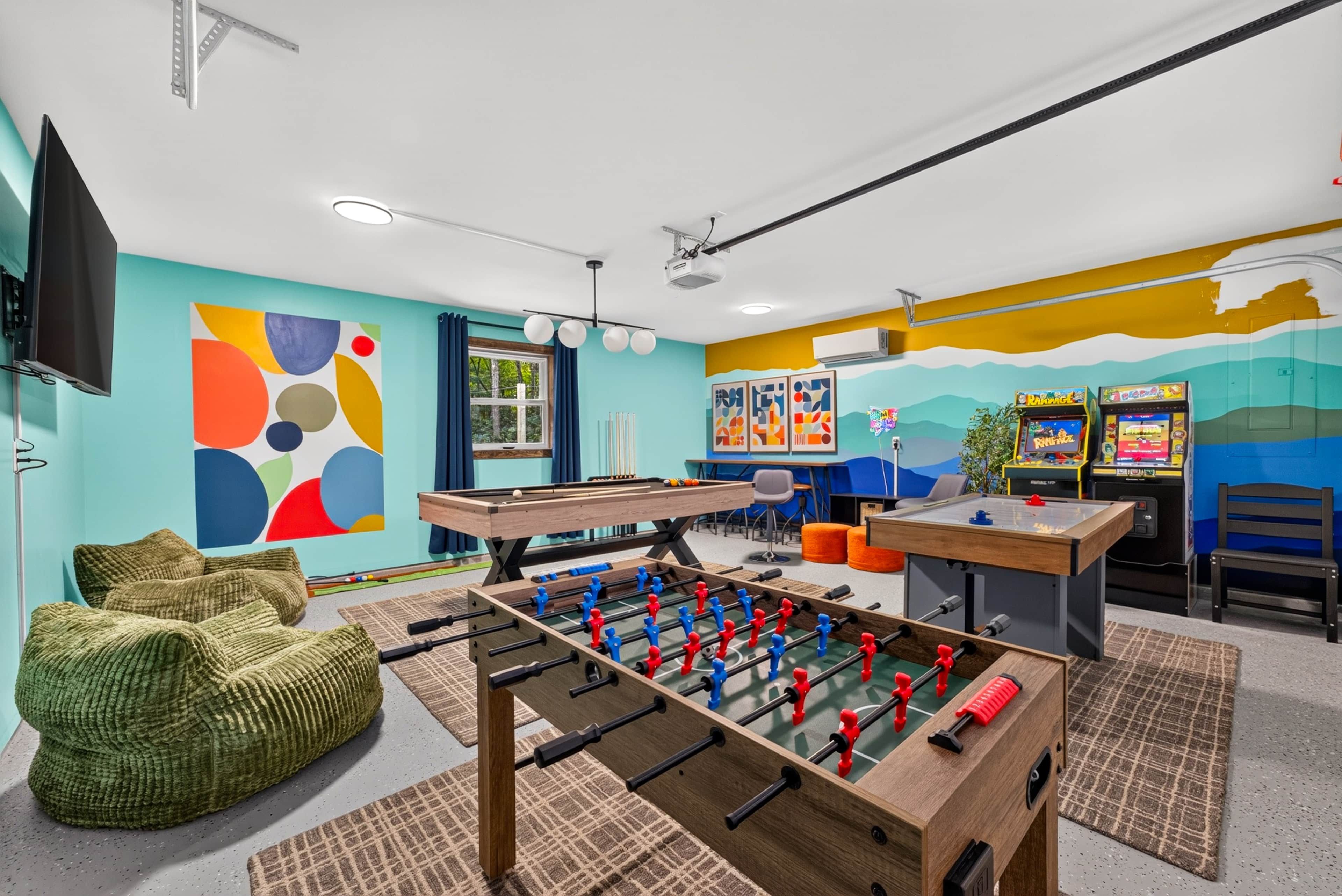 Een kamer met een tafelvoetbaltafel, een pooltafel en een televisie.