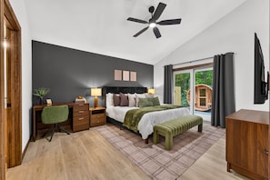 Ein Schlafzimmer mit Bett, Nachttischen, Schreibtisch, Stuhl, Deckenventilator und Blick ins Freie.