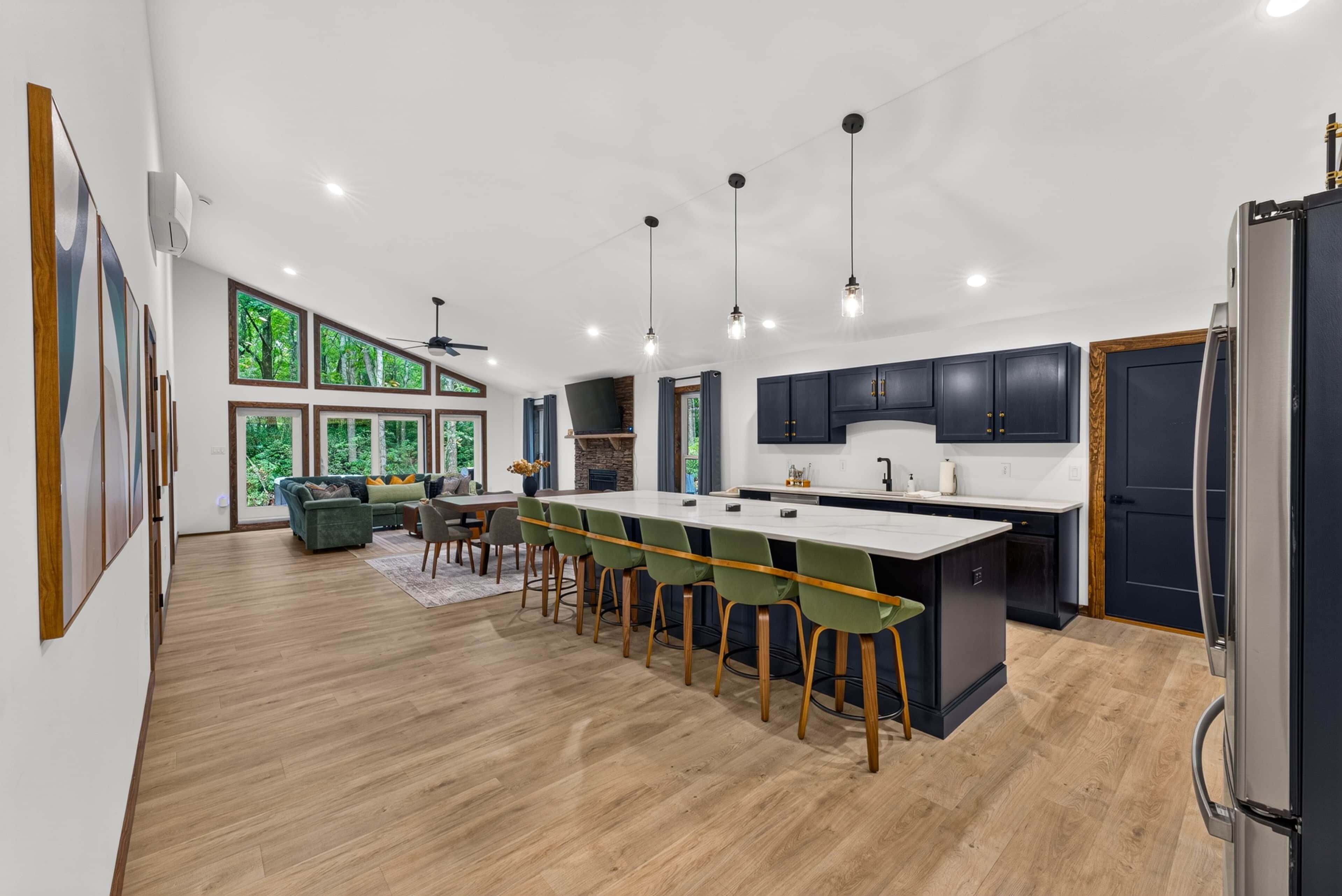 Una cocina moderna con una isla central, armarios oscuros y un comedor con sillas.