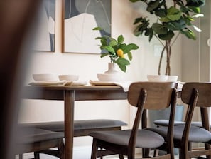 Un'area pranzo con un tavolo apparecchiato per due, sedie e un vaso con una pianta.