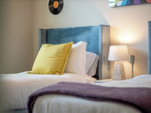 Una camera d'albergo con un letto, un comodino con una lampada e un giradischi fissato al muro.