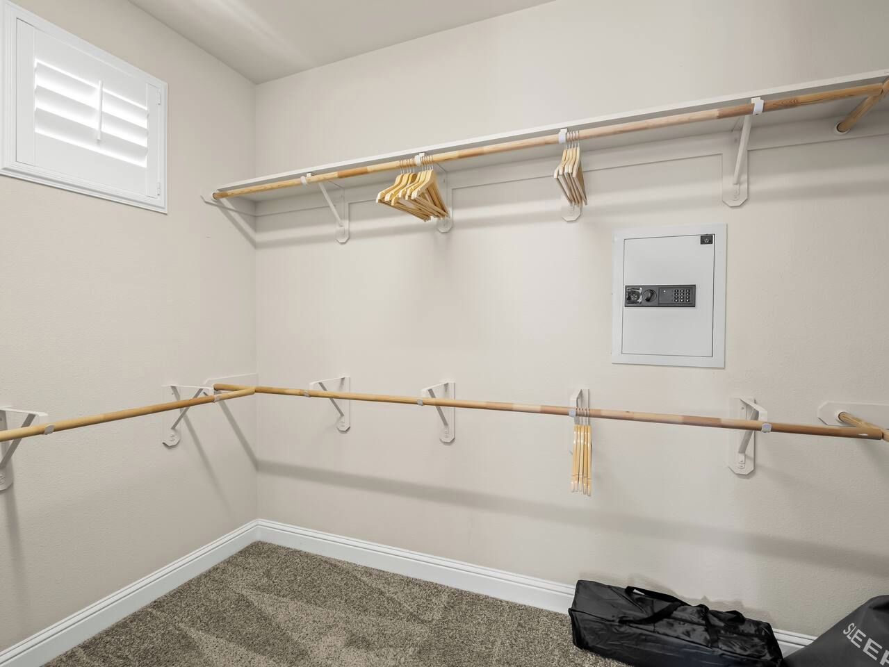Una habitación con un perchero de madera, un calentador de pared y un bolso en el suelo.