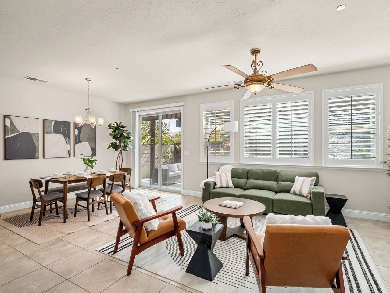 A spacious living area with a dining table, sofas, and a ceiling fan.