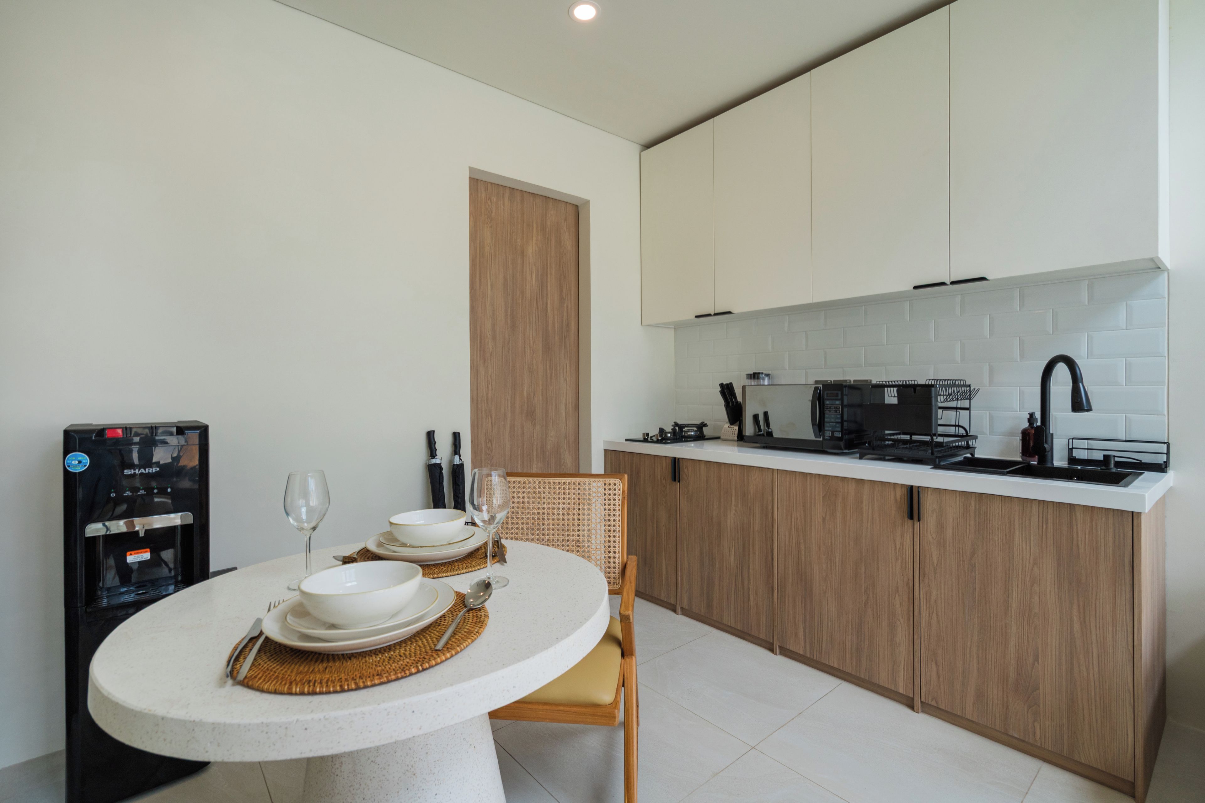 Cocina compacta con comedor, equipada con dispensador de agua, microondas y lavaplatos.