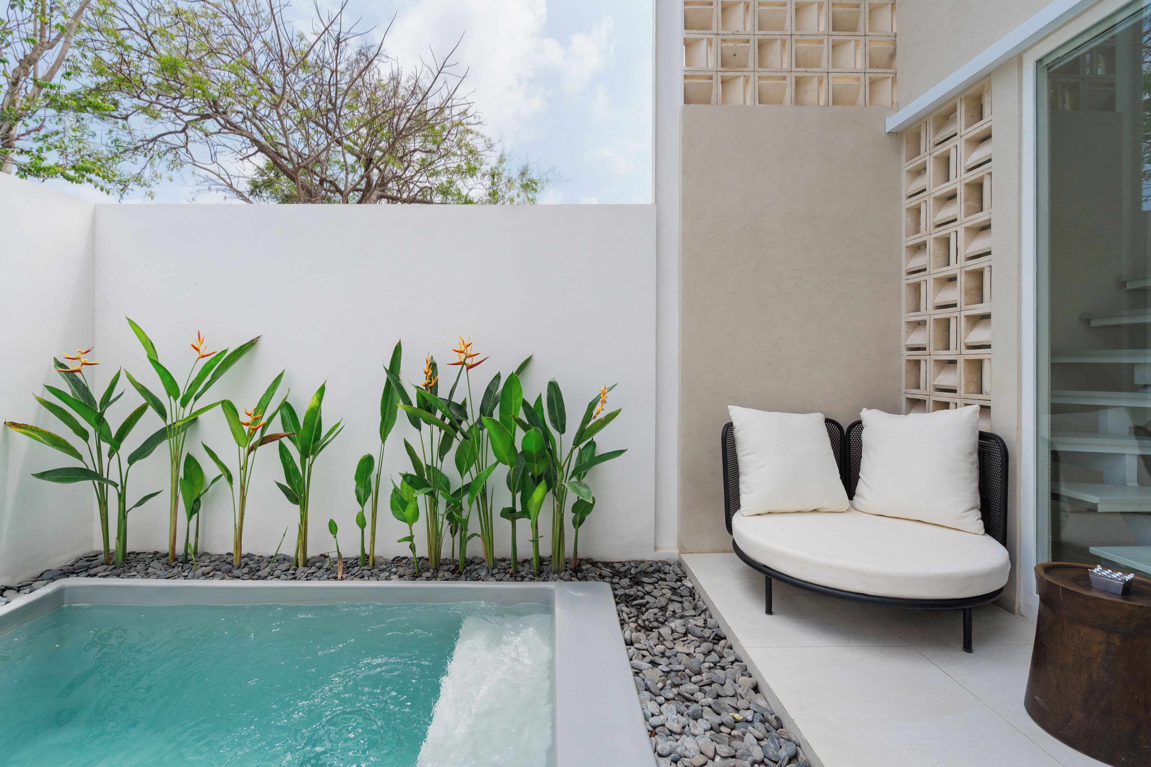 Una zona de piscina con un espacio de estar y plantas.
