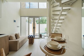 A modern interior with a dining area, a sofa, and a staircase. - Villa 21 by Betterplace (Pecatu)