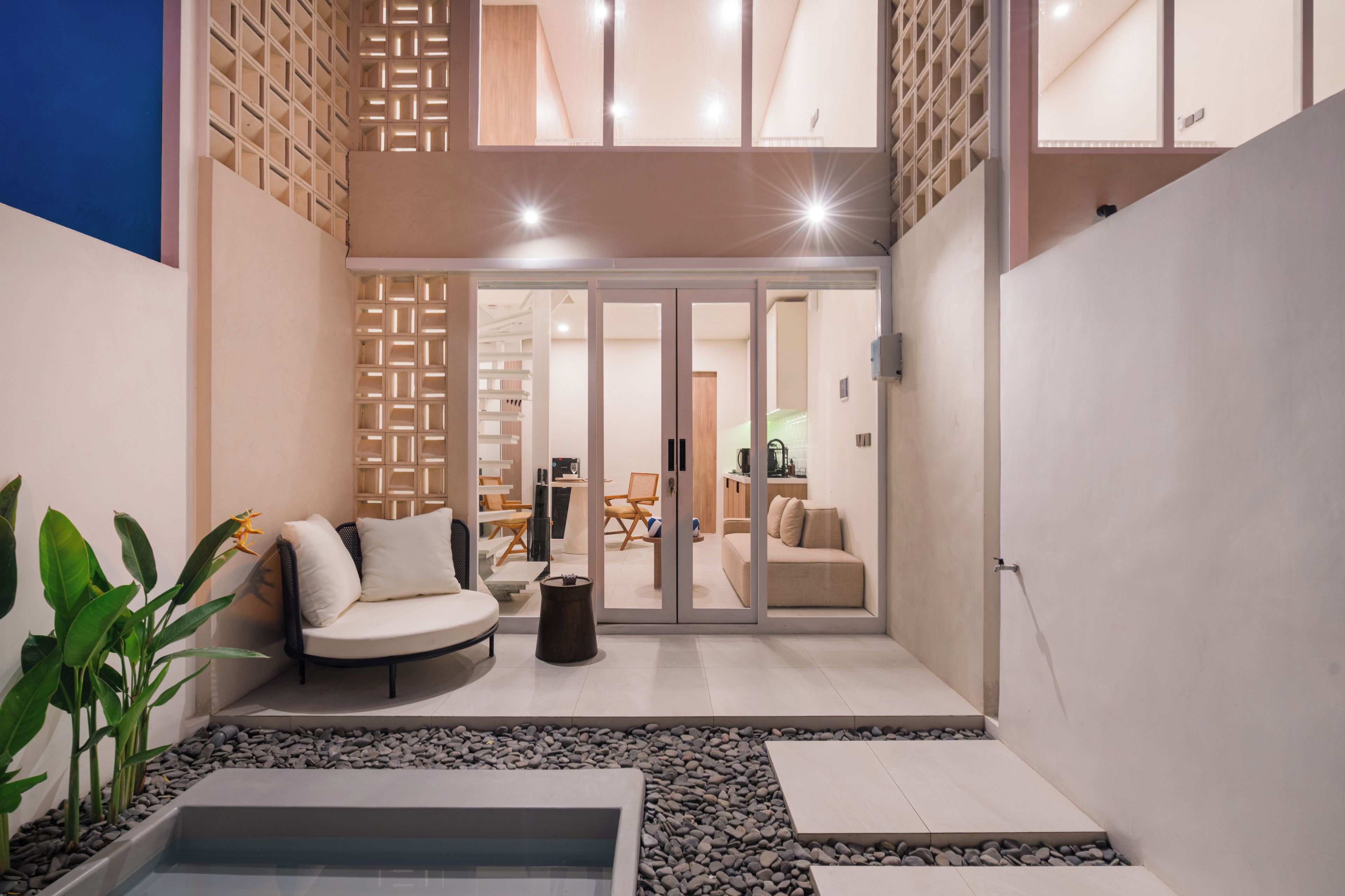 Un interior moderno con una zona de estar, una mesita y un elemento decorativo de agua.