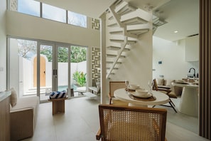 Un interior moderno con una escalera de caracol, un comedor y vistas a una piscina.