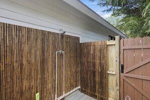 Ein Holzzaun mit einem Metallgitter, eine Bambuswand und eine kleine Holzterrasse.