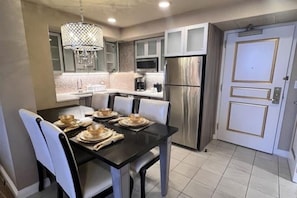 A modern kitchen with stainless steel appliances, a dining table set for four, and a chandelier. - New Year’s Eve in Las Vegas — Stay on the Strip (Las Vegas)