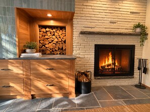 Ein Kamin mit Feuer, eine Holzkabine mit Schubladen und ein Blumentopf an der Wand.