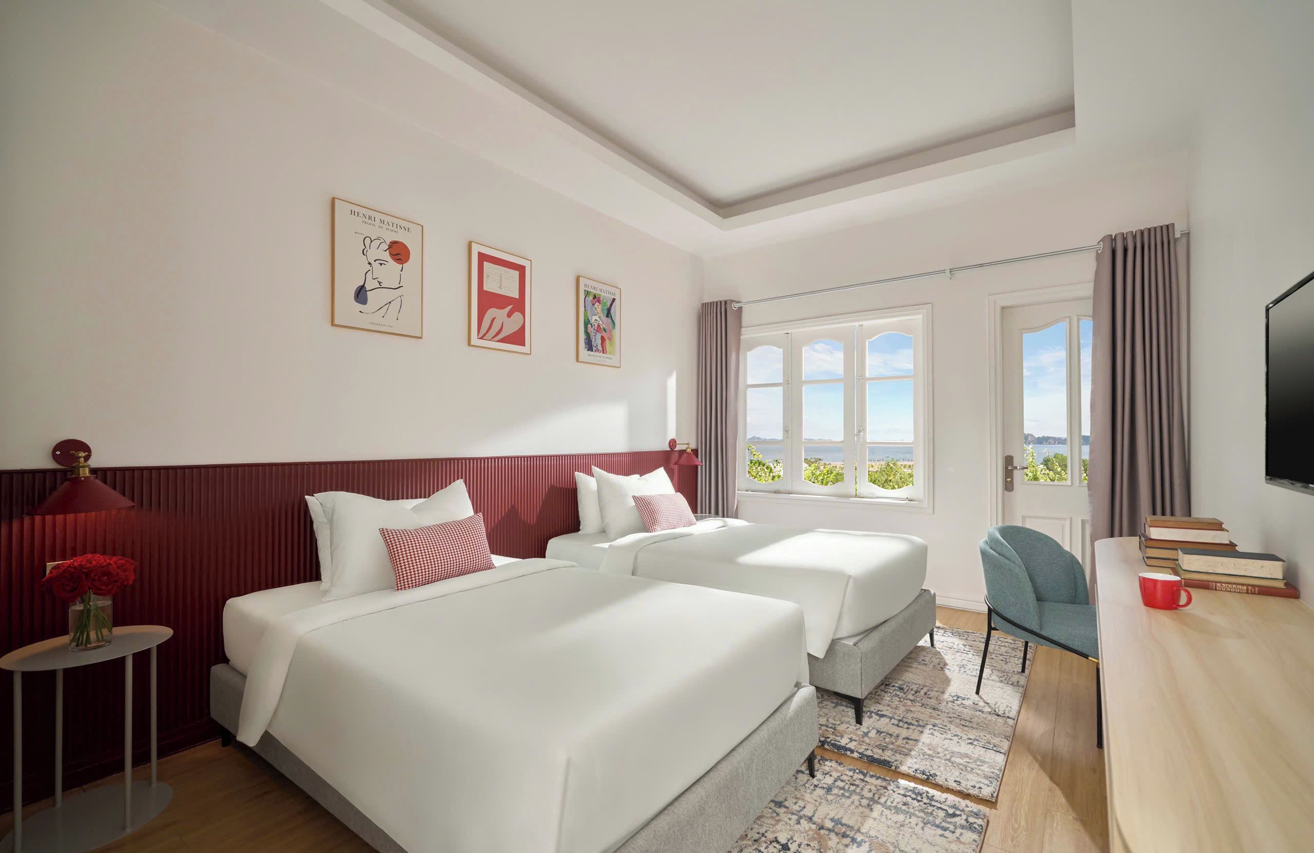 Une chambre d’hôtel avec deux lits, une télévision, un bureau avec des livres et une fenêtre donnant sur un beau paysage.