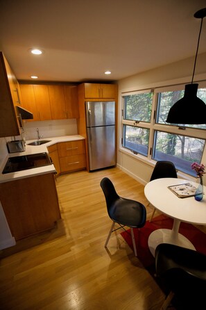 Eine moderne Küche mit Holzschränken, einem Edelstahlkühlschrank und einem Essbereich mit Tisch und Stühlen.