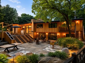 Ein modernes Holzhaus mit Terrasse, Sitzgelegenheiten und Lichterketten.
