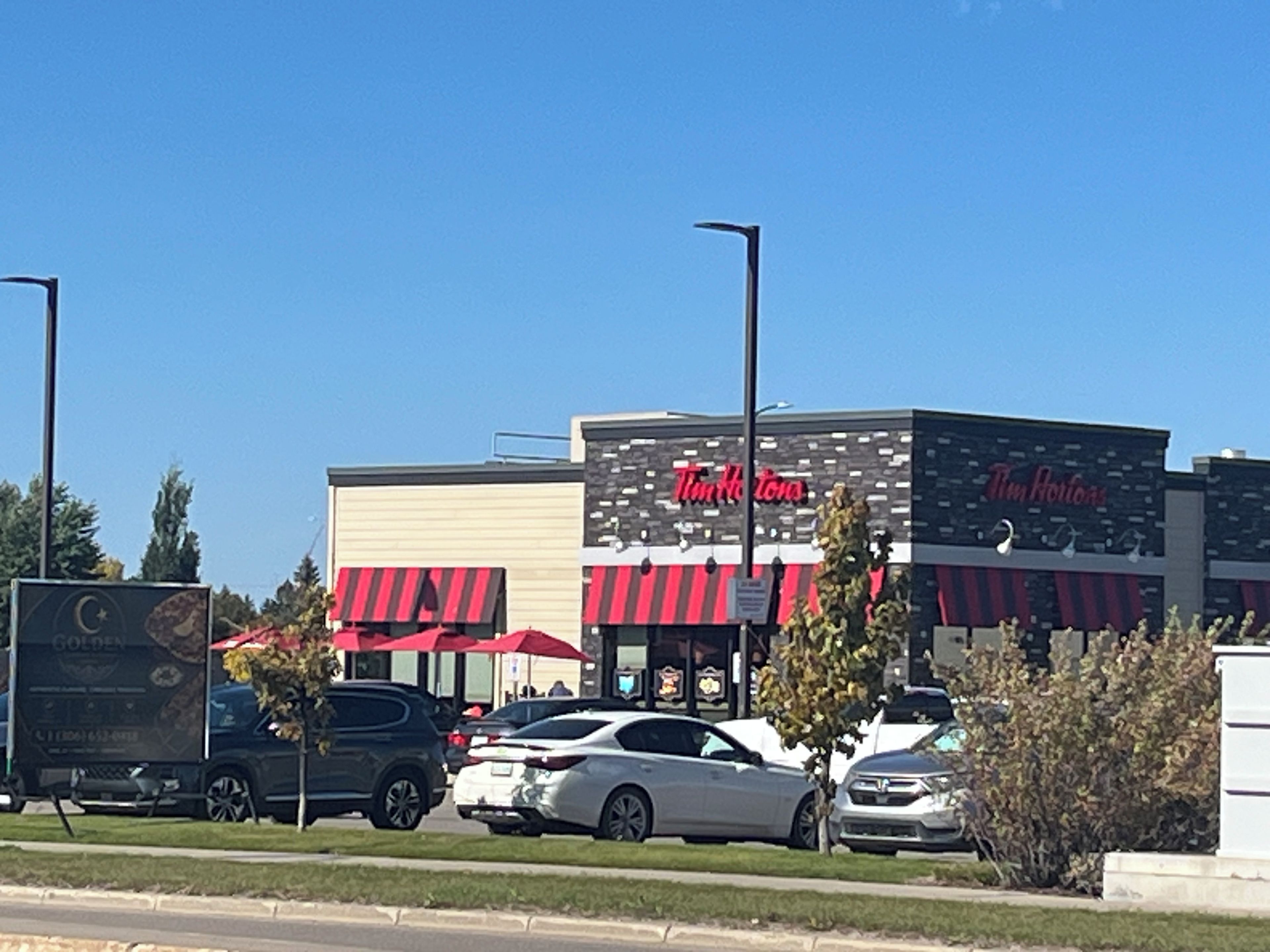 Un restaurante Tim Hortons con estacionamiento y una calle.