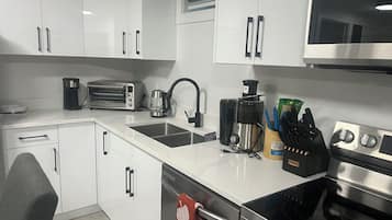 A modern kitchen with white cabinets, a stainless steel range, a coffee maker, and a toaster.